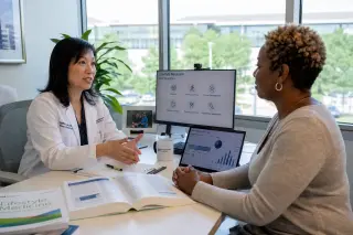 Doctor and patient discuss a non-pharmaceutical care plan in a sunlit, modern consultation room, with open medical journals and health data visible.